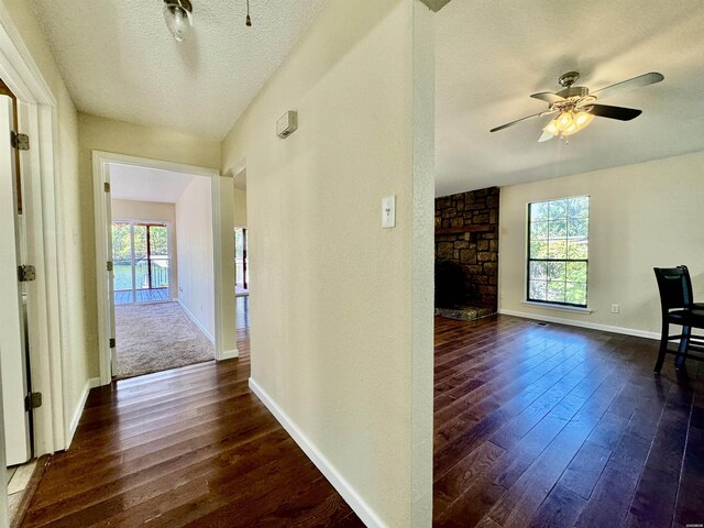 corridor featuring dark wood-style floors, a textured ceiling, and baseboards