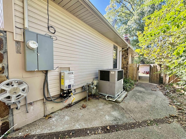 view of side of home with central air condition unit, a chimney, fence, and a patio