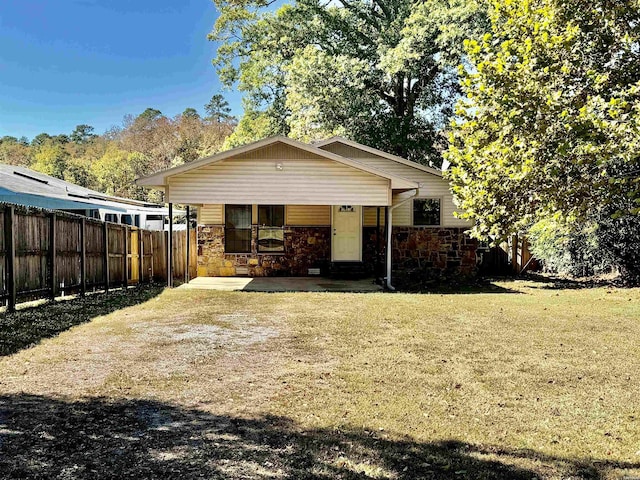 view of front of property featuring stone siding, a fenced backyard, and a front lawn