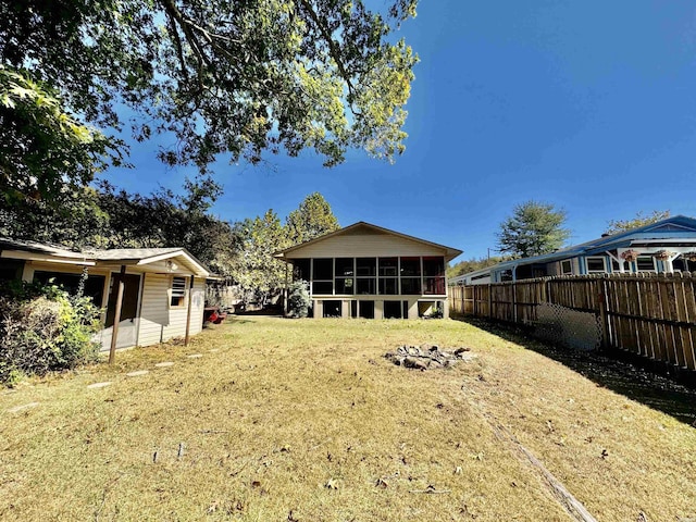 rear view of property featuring a lawn, fence private yard, and a sunroom