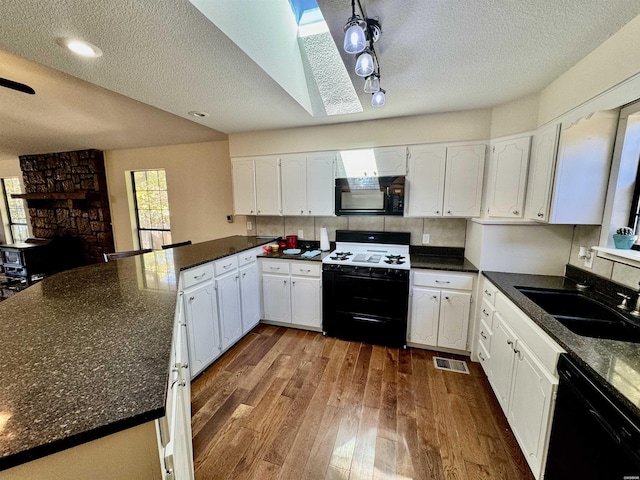 kitchen with visible vents, white cabinetry, a sink, wood finished floors, and black appliances