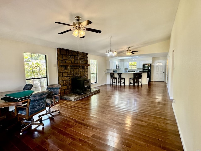 living room with ceiling fan, dark wood-type flooring, a wood stove, and baseboards