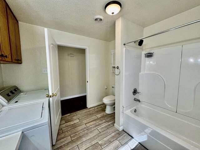 full bath with bathing tub / shower combination, toilet, independent washer and dryer, a textured ceiling, and wood finish floors