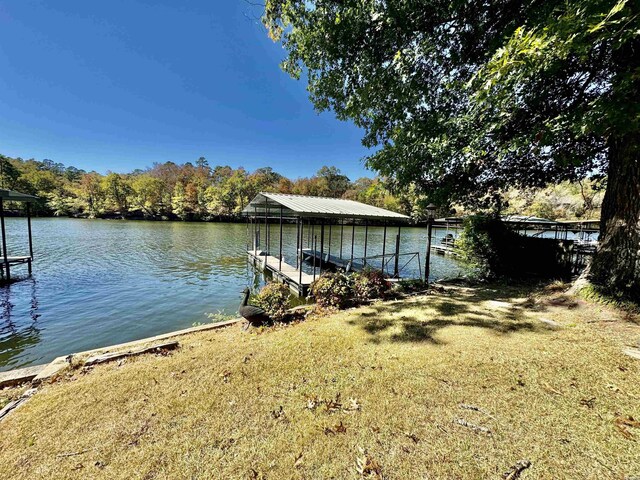 dock area with a water view, a lawn, and boat lift