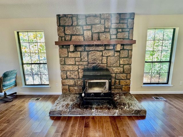 interior details featuring a wood stove, visible vents, baseboards, and wood finished floors