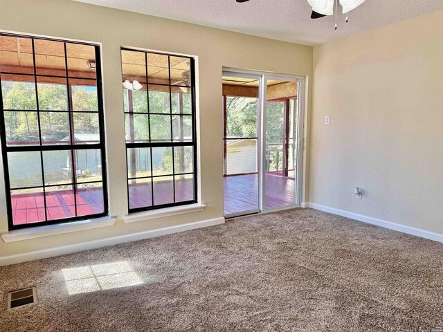 unfurnished room featuring carpet, visible vents, a ceiling fan, a textured ceiling, and baseboards