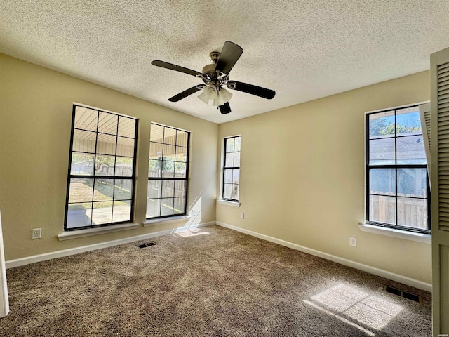 carpeted empty room featuring baseboards, ceiling fan, visible vents, and a healthy amount of sunlight