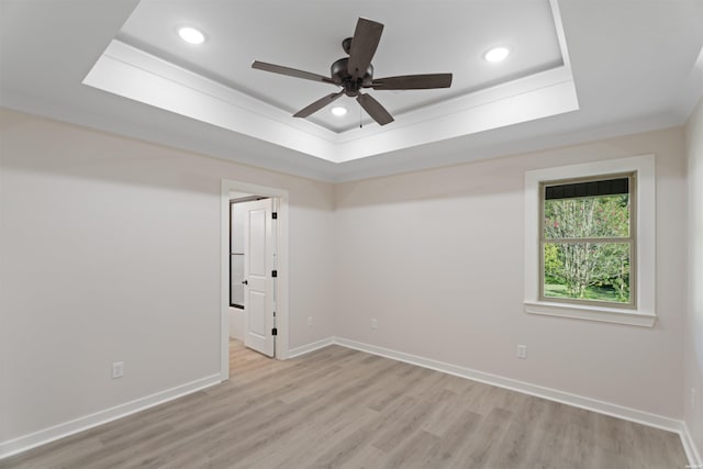 unfurnished room with light wood-style flooring, a tray ceiling, baseboards, and recessed lighting