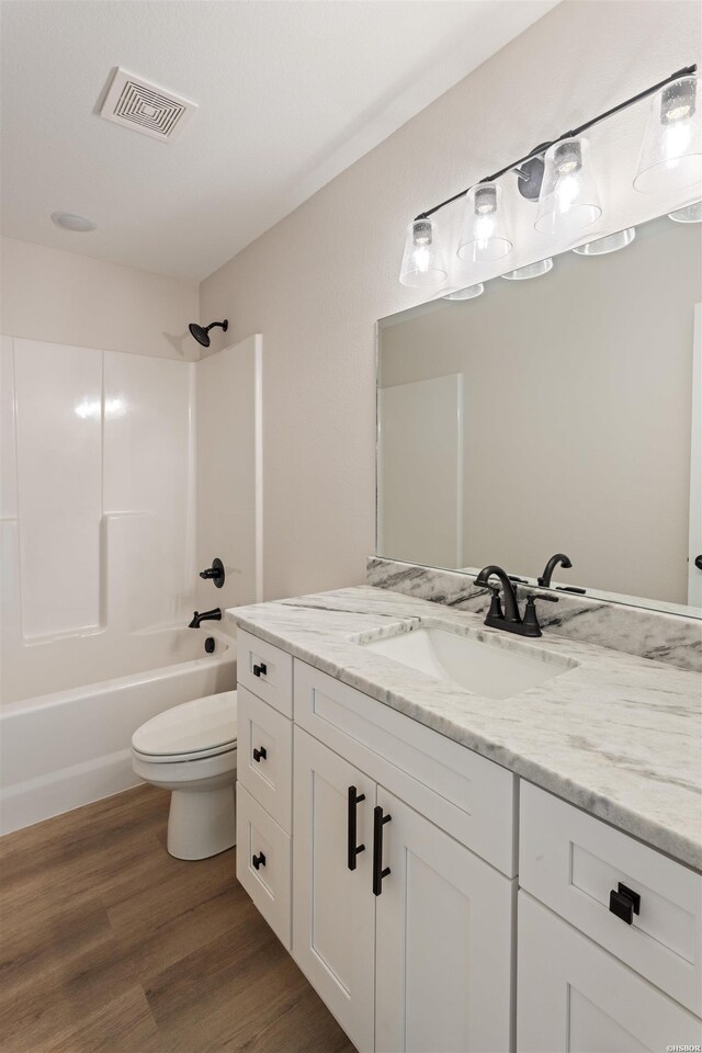 full bathroom with visible vents, toilet, shower / bathtub combination, wood finished floors, and vanity