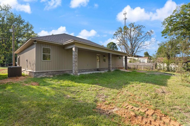 view of property exterior featuring cooling unit, brick siding, a yard, and fence