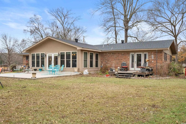 back of property with french doors, a lawn, a patio area, and brick siding