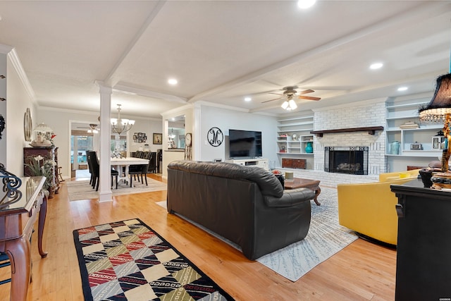 living area featuring ceiling fan with notable chandelier, light wood-type flooring, ornamental molding, and a fireplace