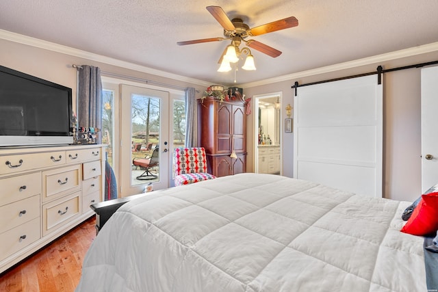 bedroom with a barn door, ornamental molding, access to outside, a textured ceiling, and light wood-type flooring