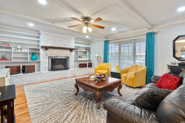 living area featuring crown molding, a fireplace, a textured ceiling, wood finished floors, and beamed ceiling