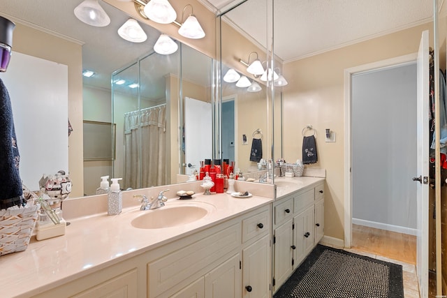 full bath featuring baseboards, double vanity, a sink, and crown molding