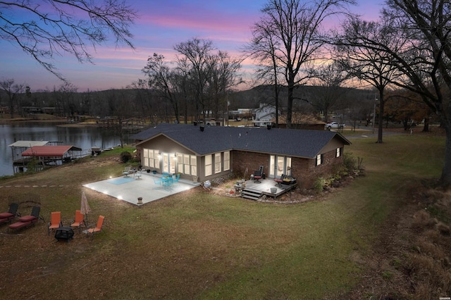 back of house with a patio area, a water view, and a lawn