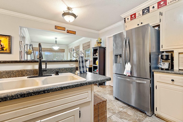 kitchen with dark countertops, crown molding, stainless steel refrigerator with ice dispenser, and a sink