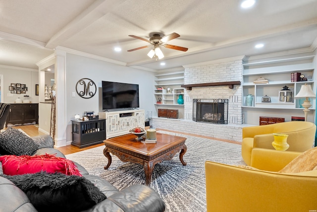 living room featuring ceiling fan, crown molding, light wood-type flooring, a brick fireplace, and built in shelves