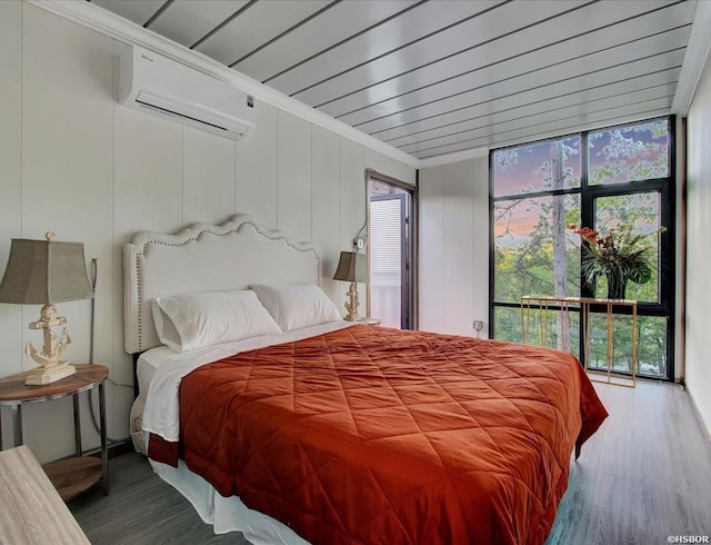 bedroom featuring an AC wall unit, floor to ceiling windows, crown molding, and wood finished floors