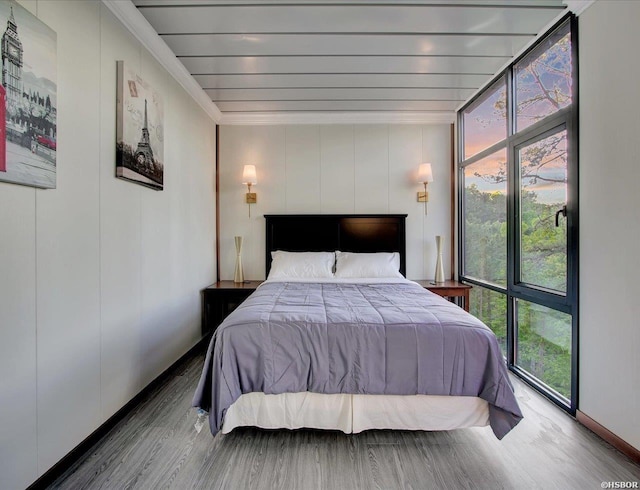 bedroom featuring ornamental molding, wood finished floors, and floor to ceiling windows