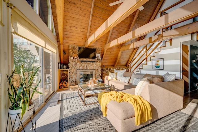 living area with beam ceiling, wooden ceiling, a stone fireplace, and wood finished floors