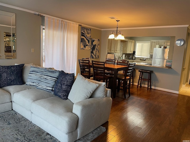 living area with dark wood-style flooring, a notable chandelier, visible vents, ornamental molding, and baseboards