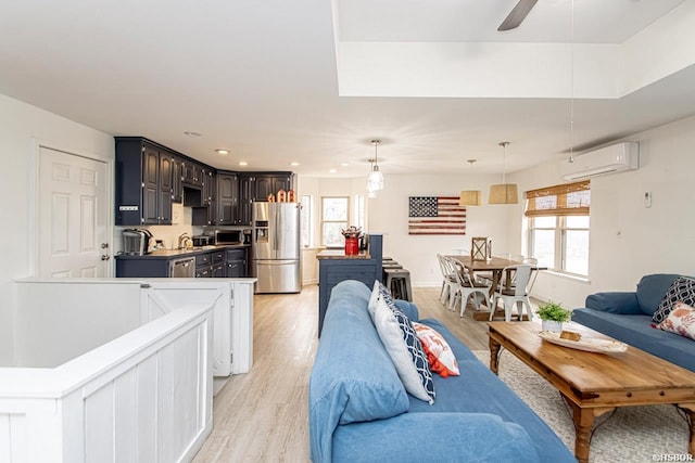 living area featuring a ceiling fan, a wall unit AC, light wood-style flooring, and recessed lighting