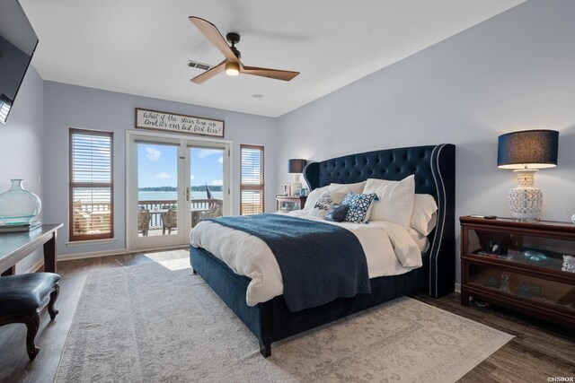 bedroom featuring access to exterior, a water view, visible vents, ceiling fan, and wood finished floors