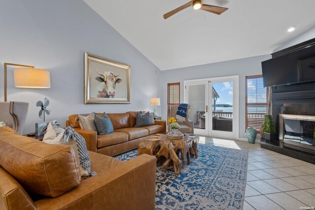 living area featuring high vaulted ceiling, a glass covered fireplace, light tile patterned flooring, and ceiling fan