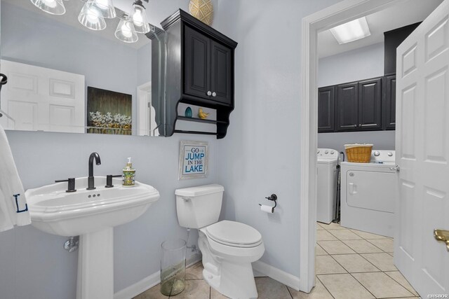 bathroom with baseboards, washing machine and dryer, toilet, and tile patterned floors