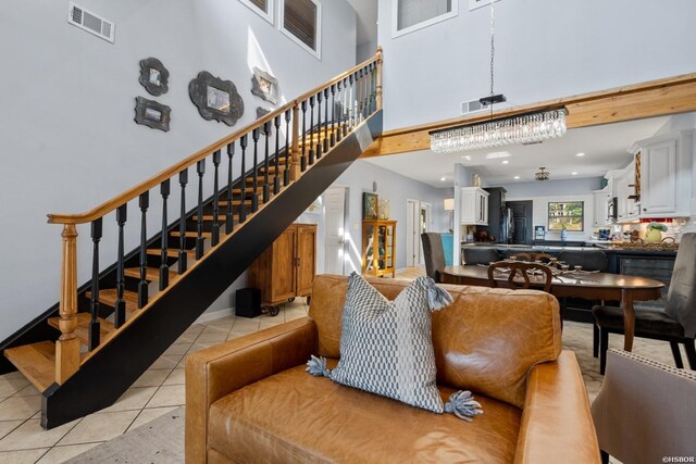 living room featuring a towering ceiling, stairs, visible vents, and light tile patterned flooring