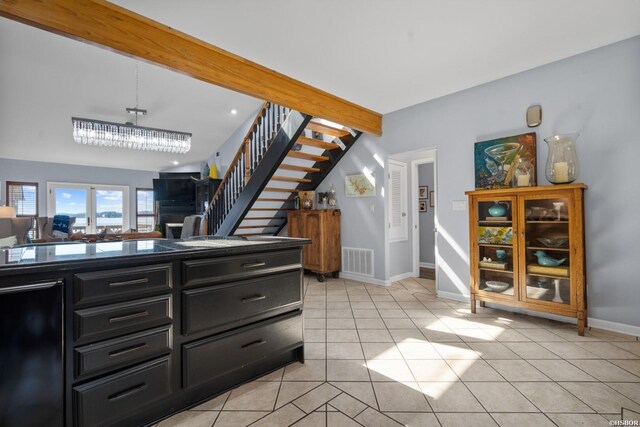 kitchen with beam ceiling, light tile patterned floors, visible vents, dark cabinets, and baseboards