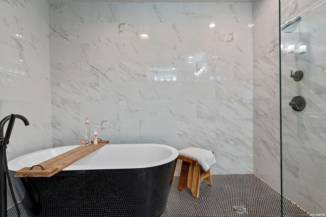 full bathroom featuring a freestanding tub, a walk in shower, and tile walls