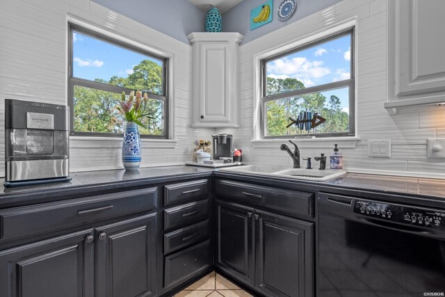 kitchen with a sink, white cabinetry, black dishwasher, dark cabinetry, and dark countertops