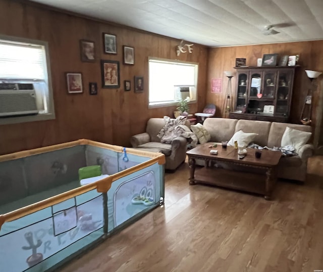 living area with cooling unit, wood finished floors, and wooden walls