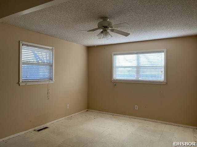 empty room featuring visible vents, ceiling fan, and a textured ceiling