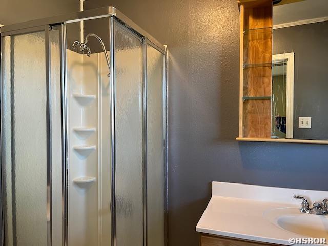 bathroom featuring a stall shower, a textured wall, and vanity