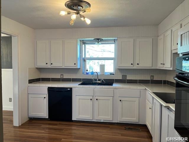 kitchen with dark wood-style flooring, tile countertops, white cabinetry, a sink, and black appliances