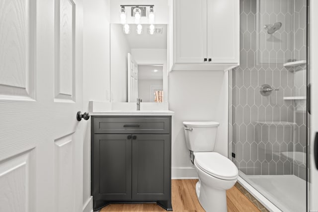 bathroom with wood finished floors, a shower stall, toilet, and vanity