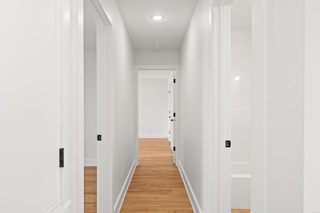 corridor featuring light wood finished floors and baseboards