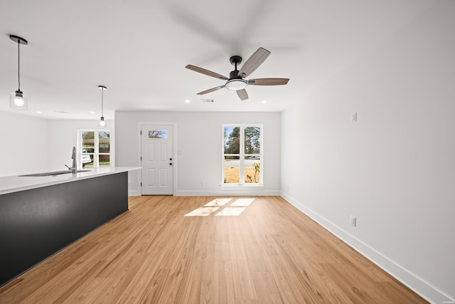 unfurnished living room with recessed lighting, visible vents, light wood-style flooring, a sink, and baseboards