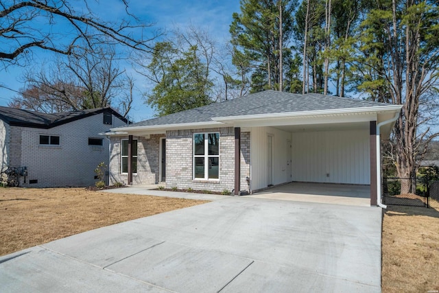 ranch-style home with roof with shingles, a front yard, concrete driveway, and brick siding