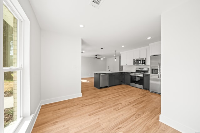 kitchen featuring a peninsula, a healthy amount of sunlight, visible vents, and stainless steel appliances