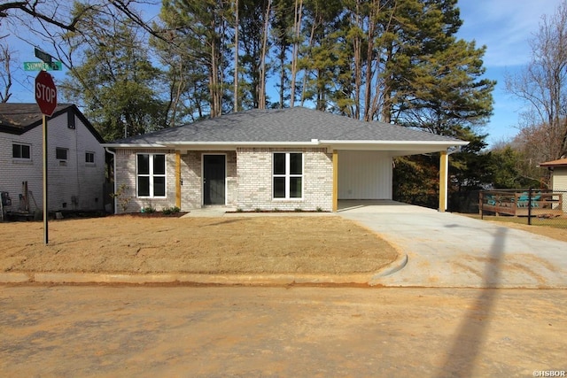 view of front of home featuring a shingled roof, concrete driveway, and brick siding