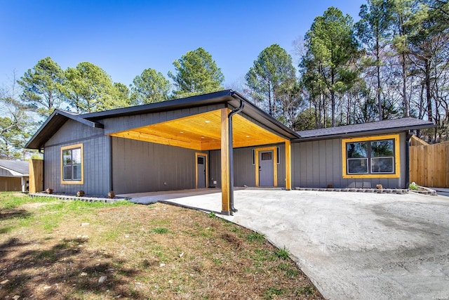 mid-century modern home with driveway, fence, and an attached carport