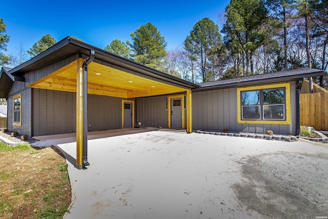 mid-century inspired home featuring a carport, fence, driveway, and board and batten siding