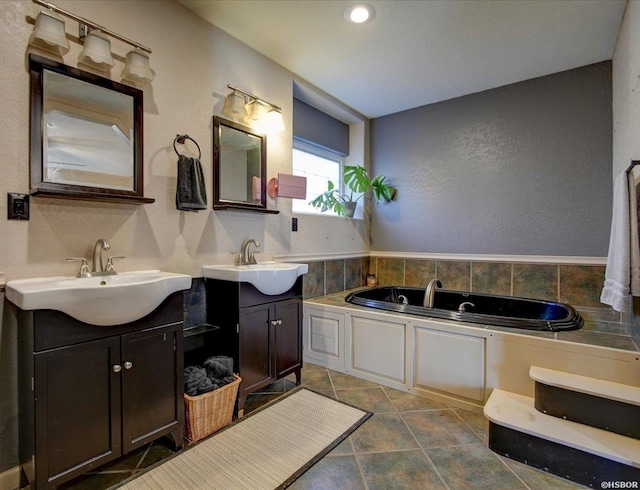 bathroom featuring a garden tub, a textured wall, and vanity