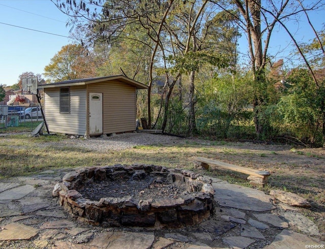 view of yard with an outdoor structure, a fire pit, and a shed