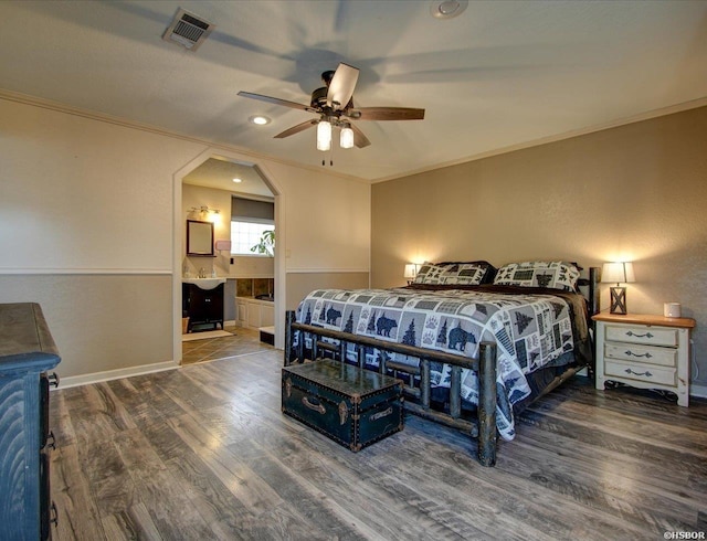 bedroom with visible vents, dark wood finished floors, arched walkways, ensuite bath, and ornamental molding