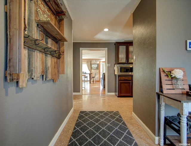 corridor featuring recessed lighting, baseboards, ornamental molding, and a textured wall